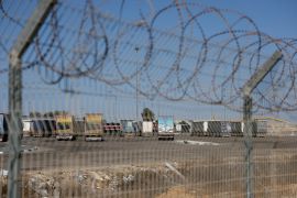 Trucks carrying aid await at the Israeli side of the Karem Abu Salem crossing to southern Gaza on October 20, 2025 [Hannah McKay/Reuters]