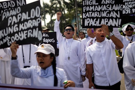 Filipino members of the clergy shout and raise placards during an anti-corruption protest over widespread corruption allegations linked to government infrastructure projects