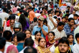 A man speaks on his mobile phone as he walks through a crowded market in Varanasi, India [File: Niharika Kulkarni/AFP]