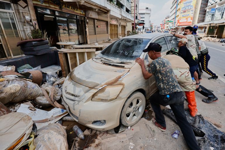 Peoples move a car damaged from floods in Songkhla province, southern Thailand, Sunday, Nov. 30, 2025. (AP Photo/Sarot Meksophawannakul)