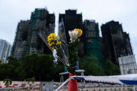 People offer flowers for the victims near the site of Wednesday&#039;s fire at Wang Fuk Court, a residential estate, in the Tai Po district of Hong Kong, November 30, 2025 [Chan Long Hei/AP]