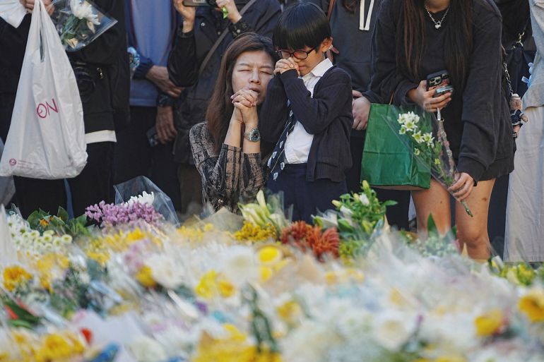 People pray as they lay flowers at a makeshift memorial near Wang Fuk Court housing estate to pay tribute to victims of the deadly fire at the housing complex, in Tai Po, Hong Kong, China, on Dec. 1, 2025. [Lam Yik/Reuters]