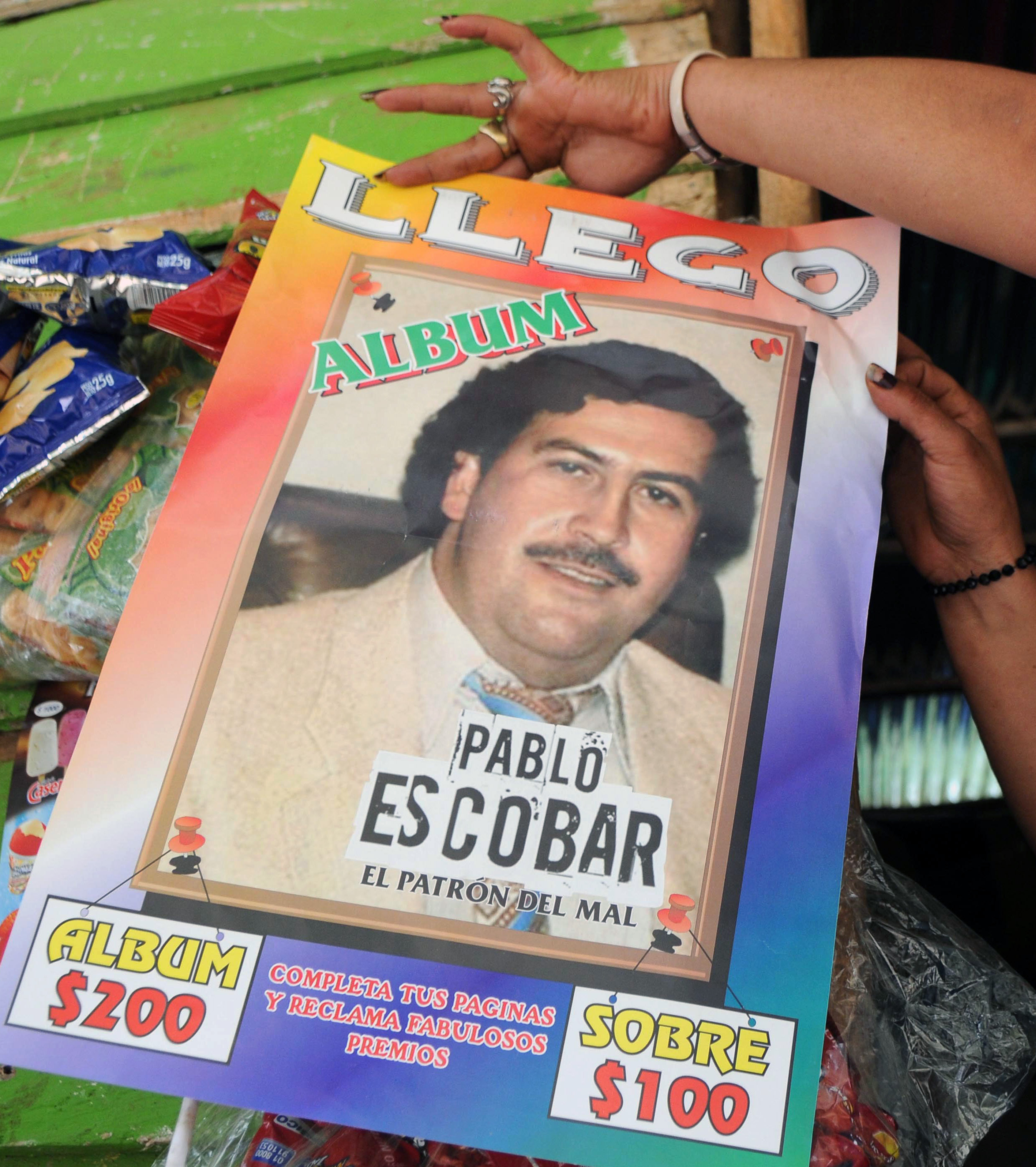 A woman shows a poster promoting a magazine style publication about the life of the late Escobar in Medellin [Luis Benavides/AP Photo]