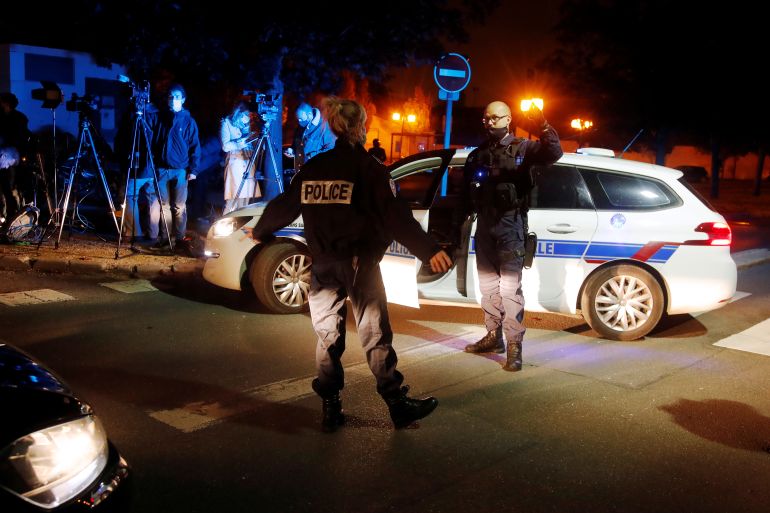 Police officers secure the area near the scene of a stabbing attack in the Paris suburb of Conflans St Honorine, France