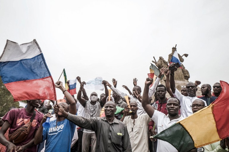 Russian and Malian flags are waved by protesters in Bamako