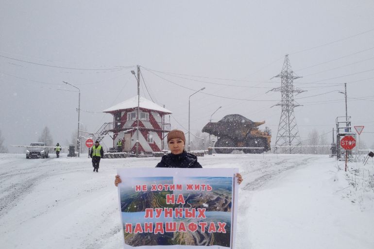Yana Tannagasheva, a Shor activist, stands in the snow holding a banner that says: "We don't want to live in moonscapes."