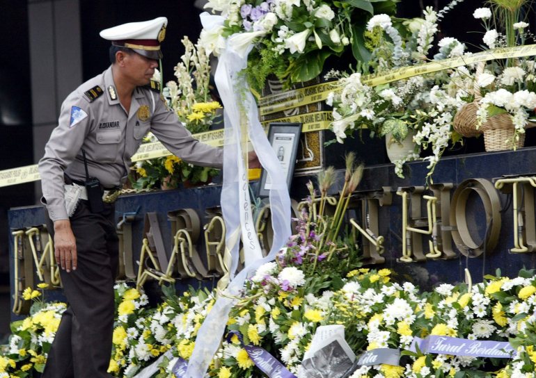An Indonesian police officer looks at the bouquets of white flowers left at the mangled signboard of Jakarta's JW Marriott Hotel as prayers were hekd for those killed in the August 2003 bombing