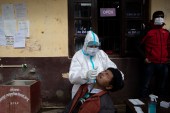 A Nepalese man reacts as a health worker collects a swab sample during a COVID-19 antigen test in Dakshinkali municipality, on the outskirts of Kathmandu [File: Narendra Shrestha/EPA]