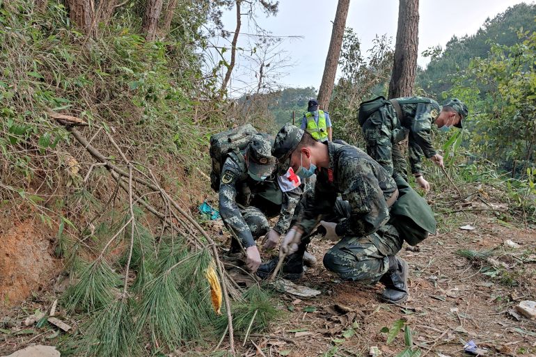 Paramilitary police officers work on the hillside where a China Eastern plane crashed on Momday