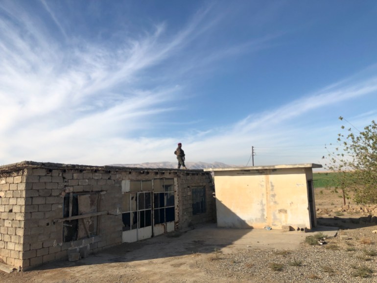 A photo of a Kurdish Peshmerga soldier standing guard on top of a building.