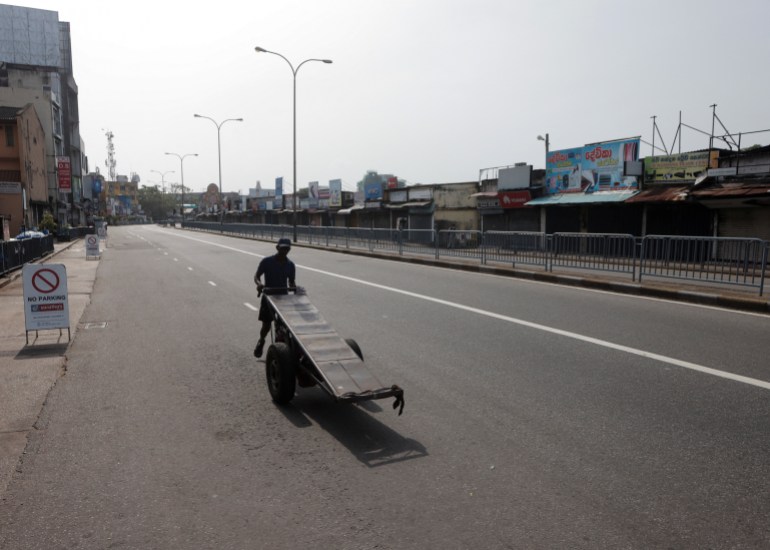 A man pushes a cart along a deserted road after the curfew was extended in Colombo, Sri Lanka.