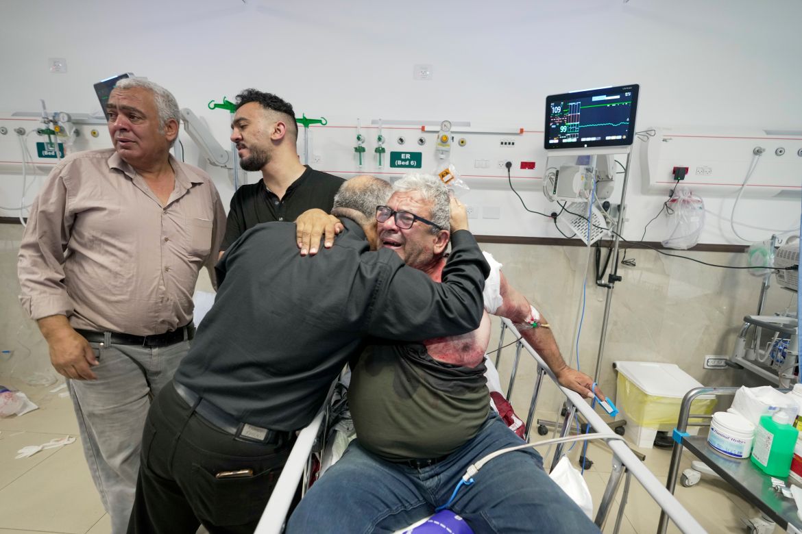 An injured journalist is being hugged by one of the colleagues of killed journalist Shireen Abu Akleh
