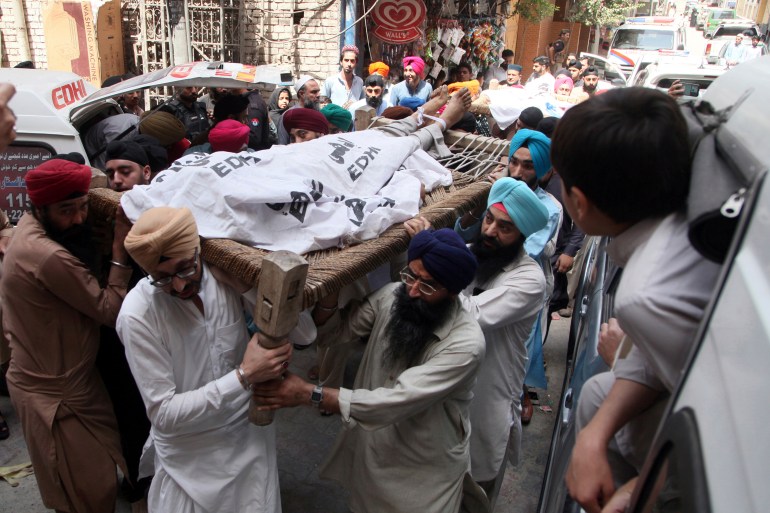 Pakistani Sikhs carry the body of a Sikh who was killed by gunmen in Peshawar, Pakistan on Sunday, May 15, 2022[ Mohammad Zubair/AP]