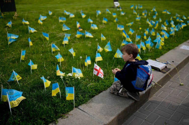A boy watches flags honoring soldiers killed fighting Russian troops in downtown Kyiv, Ukraine, Monday, May 23, 2022