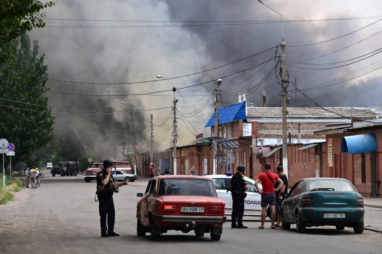 Security personnel halt motorists as smoke rises from the central market of Sloviansk