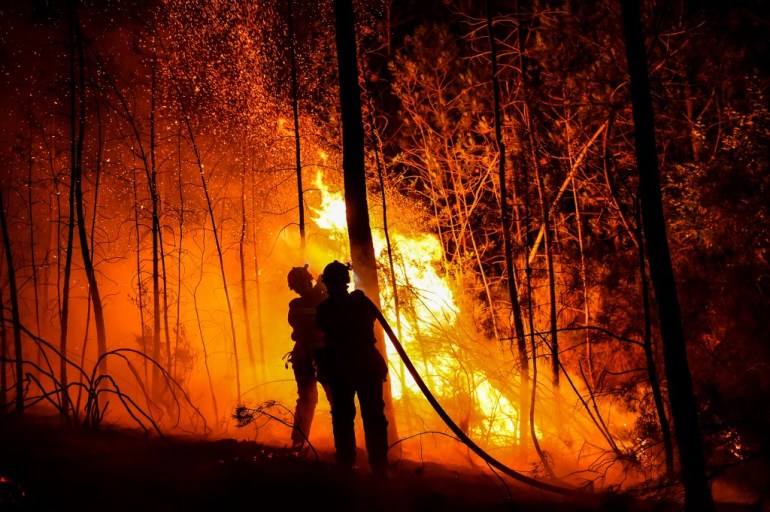 Firefighters spray water to extinguish a wildfire near Besseges, southern France