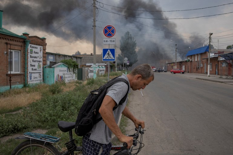 A man pushes a bicycle across a street in front of the market after shelling, in Sloviansk.
