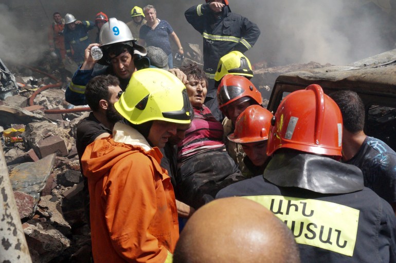 Firefighters evacuate a wounded woman at Surmalu market in Yerevan, Armenia