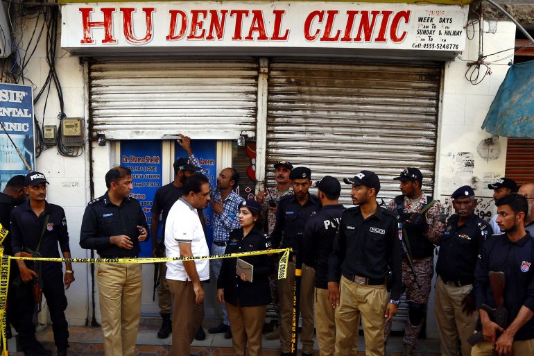 Police officers and paramilitary soldiers gather in front of the Hu Dental Clinic.