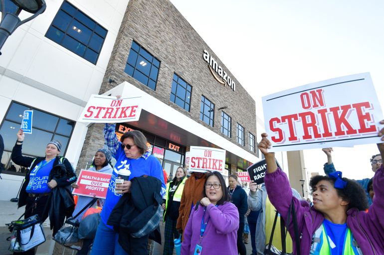 Workers outside Amazon offices hold signs saying 'ON STRIKE' and 'Health and Safety over Profits'