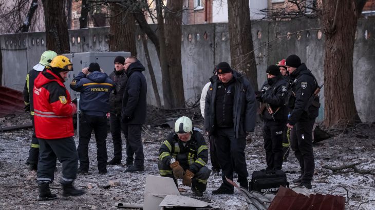 Rescuers and police officers examine parts of the drone at the site of a building destroyed by a Russian drone attack