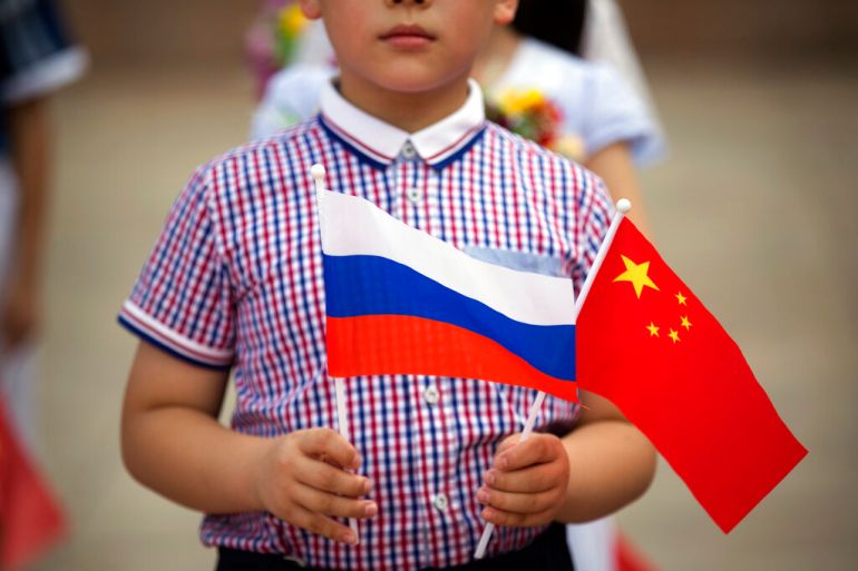FILE - A boy holds Russian and Chinese flags before a welcoming ceremony for Russian President Vladimir Putin at the Great Hall of the People in Beijing on June 25, 2016. Three weeks ago, on the eve of the Beijing Winter Olympics, the leaders of China and Russia declared that the friendship between their countries "has no limits." But that was before Russia's invasion of Ukraine, a gambit that will test just how far China is willing to go. (AP Photo/Mark Schiefelbein, File)