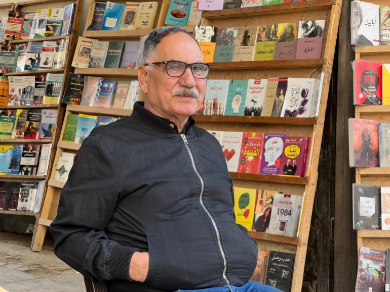Bookseller Jaafar Karim stands in front of a bookshelf full of books