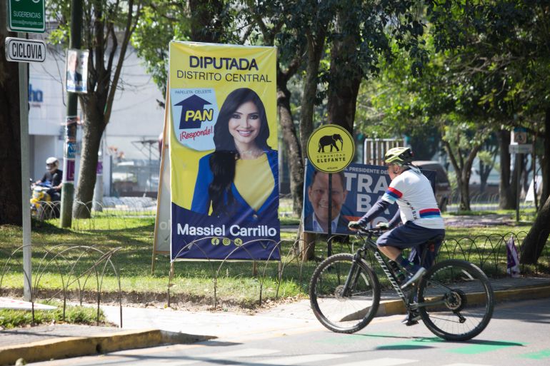 A man rides a bicycle past signs for political candidates