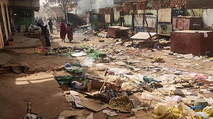 People walk among scattered objects in the market of El Geneina, the capital of West Darfur, as fighting continues in Sudan