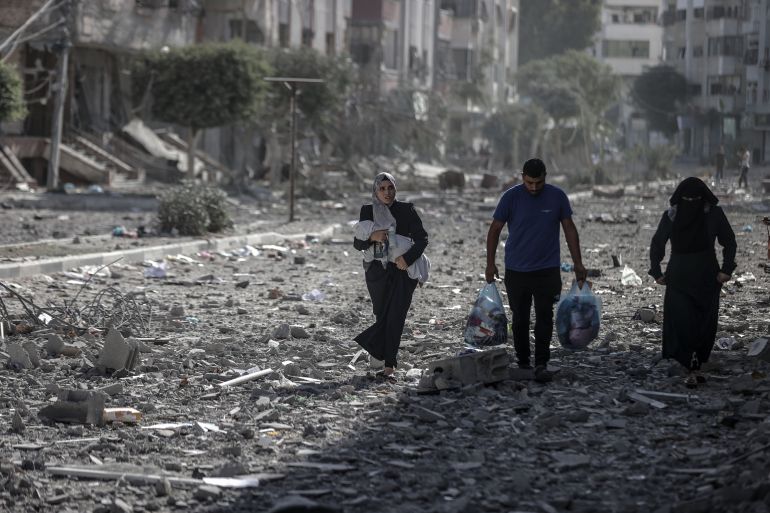 GAZA CITY, GAZA - OCTOBER 30: A woman walks with a baby amid heavily damaged buildings in Tel al-Hawa neighborhood as Israeli attacks continue to cause destruction on the 24th day in Gaza City, Gaza on October 30, 2023. ( Ali Jadallah - Anadolu Agency )