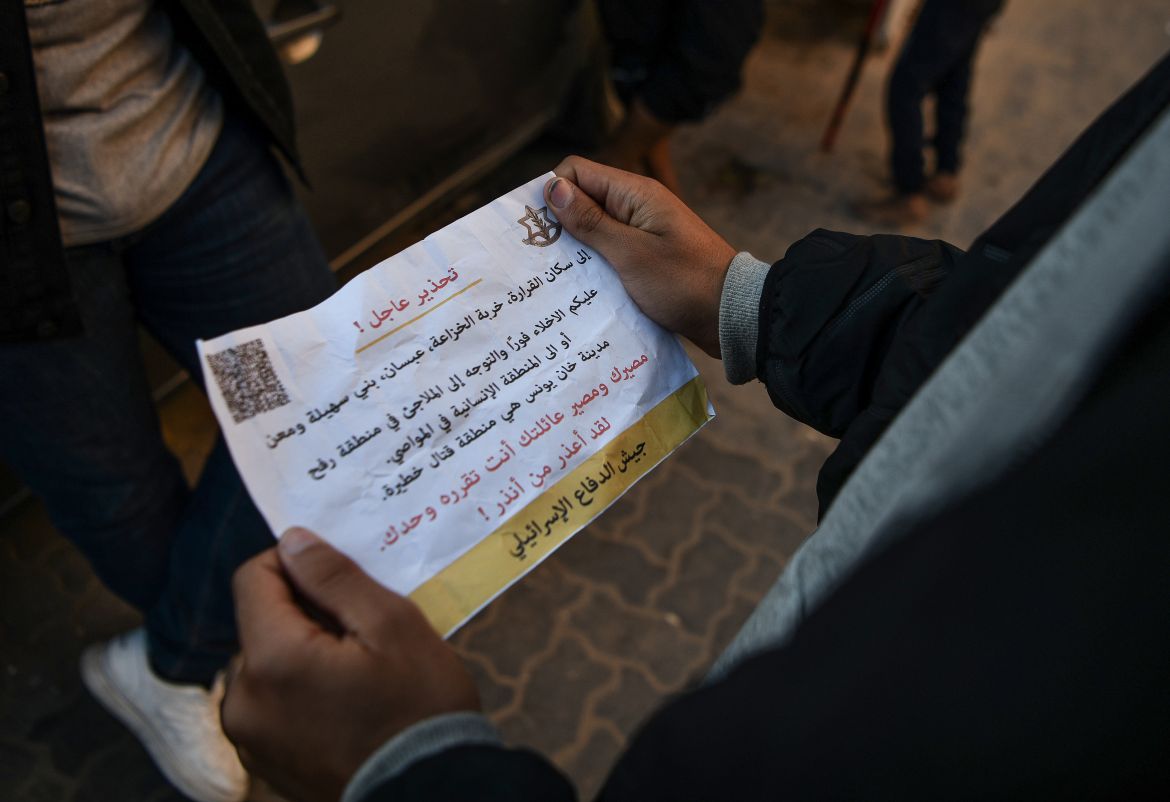A Palestinian holds a leaflet dropped by Israeli forces, urging residents to leave Al-Qarara, Khuza'a, Bani Suheila and Maan regions of the city in Khan Yunis, Gaza.
