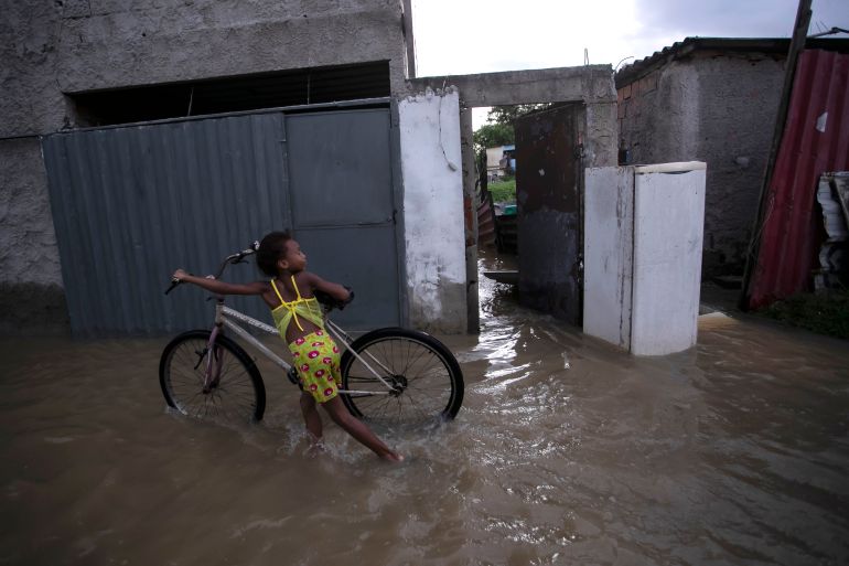 A child pushes a bicycle in a flooded street after deadly, heavy rainfall in Duque de Caxias, Brazil