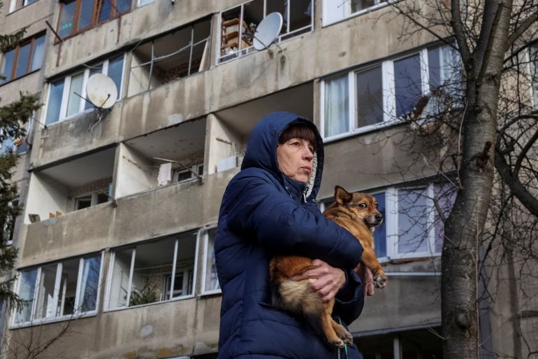 A local resident holds her dog as she stands near her apartment building damaged