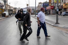 Illegal Israeli settlers walk with batons and axes along a street as Israeli settlers attacked Palestinian residents and shops in the town of Huwara in the occupied West Bank on October 13, 2022 [File: Oren Ziv/AFP]