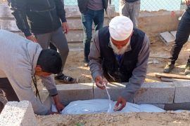 Abu Jawad buries a 14-year-old child shot by an Israeli sniper in Khan Younis [Abubaker Abed/Al Jazeera]