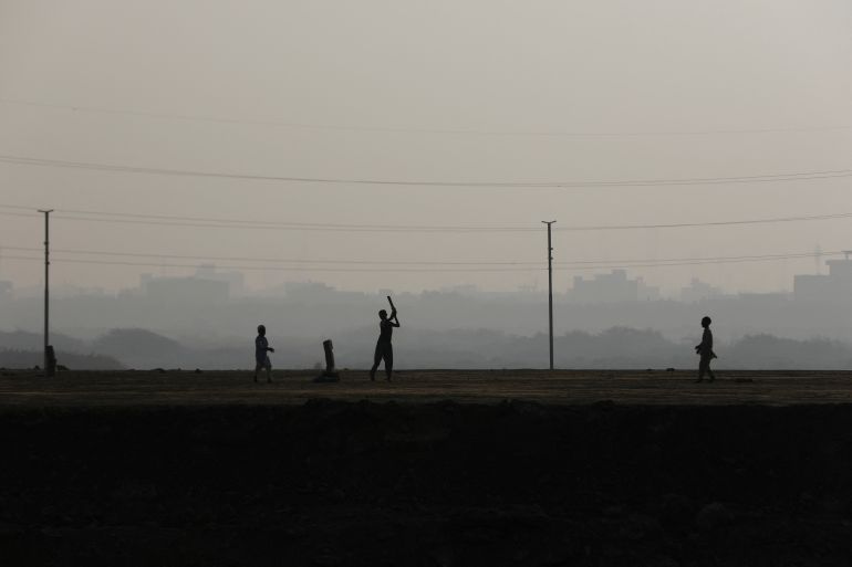 Children are silhouetted as they play cricket amid smog, as air pollution levels rise in Karachi, Pakistan.