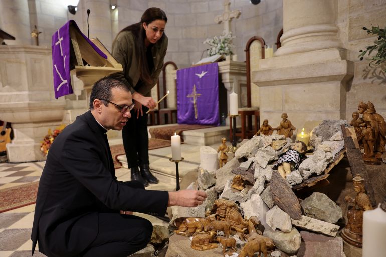 Pastor Munther Isaac adds dirt to an installation that shows a figure symbolizing baby Jesus lying amidst the rubble in a grotto ahead of Christmas at the Evangelical Lutheran Church, amid the ongoing conflict between Israel and the Palestinian Islamist group Hamas, in Bethlehem, in the Israeli-occupied West Bank, December 5, 2023. REUTERS/Mussa Qawasma