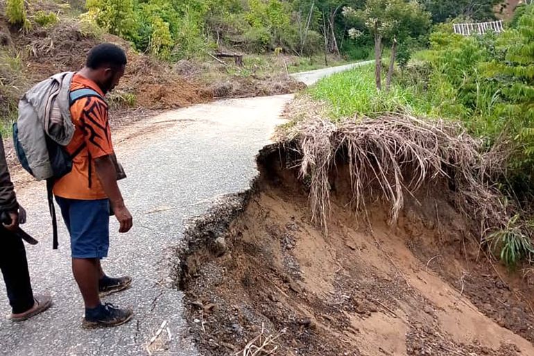 a man inspects a damaged road