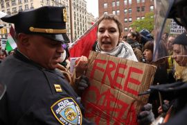 A demonstrator holds a placard near a police officer, during a protest in solidarity with Pro-Palestinian organizers on the Columbia University campusApril 18, 2024. [Caitlin Ochs/Reuters] (Reuters)