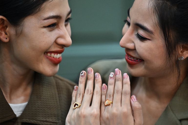 Two women showing their hands with rings on their left fingers.
